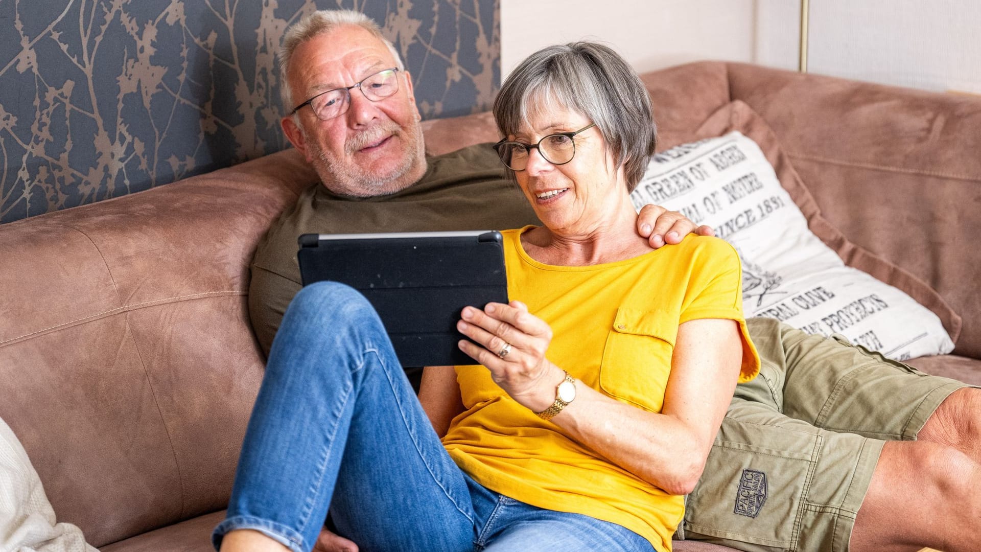 Ein Paar sitzt schaut auf ein Tablet Ein Paar sitzt schaut auf ein Tablet