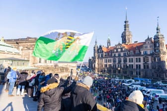 Ein Mann schwenkt eine Fahne des einstigen Königreiches Sachsen: Die Fahnen werden häufig von Anhängern der rechtsextremen Kleinstpartei getragen – und von der Partei selbst verkauft.