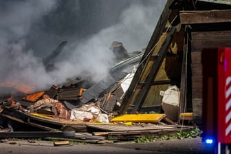 Ein Fahrzeug der Feuerwehr steht vor einem in Trümmern liegenden Haus im nordrhein-westfälischen Alpen.