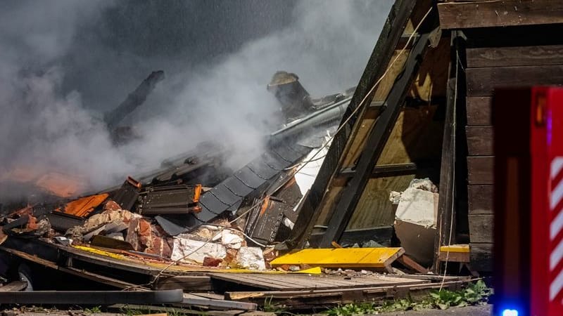 Ein Fahrzeug der Feuerwehr steht vor einem in Trümmern liegenden Haus im nordrhein-westfälischen Alpen.