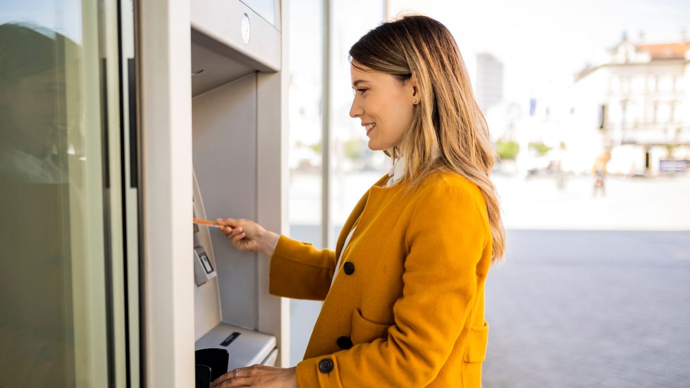 Eine Frau hebt Geld ab: Tagesgeld lässt sich schnell aufs Girokonto umbuchen.