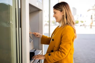 Eine Frau hebt Geld ab: Tagesgeld lässt sich schnell aufs Girokonto umbuchen.