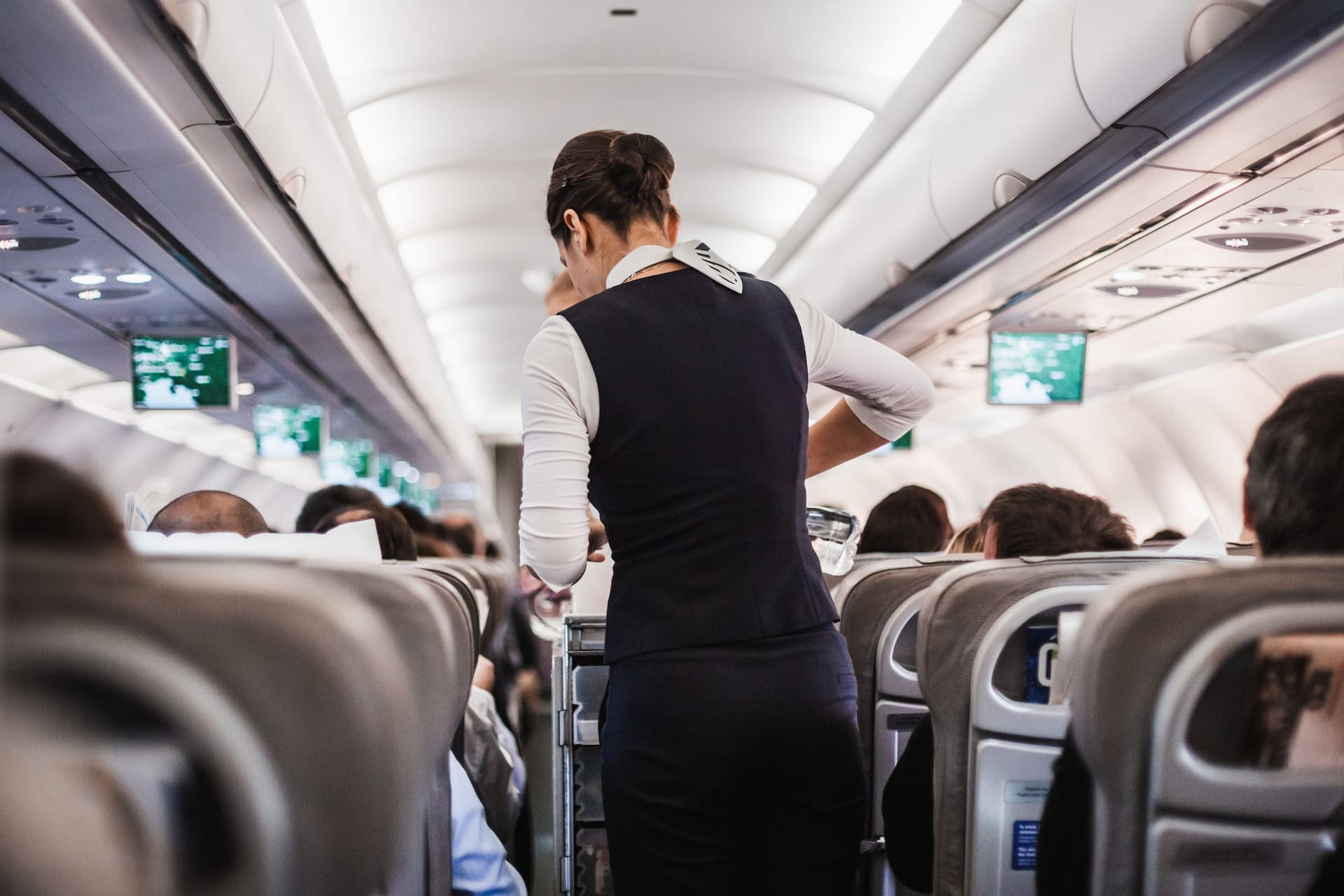 Eine Stewardess geht mit einem Getränkewagen durch ein Flugzeug (Symbolbild): Den Mann erwarten nun mehrere Anzeigen.