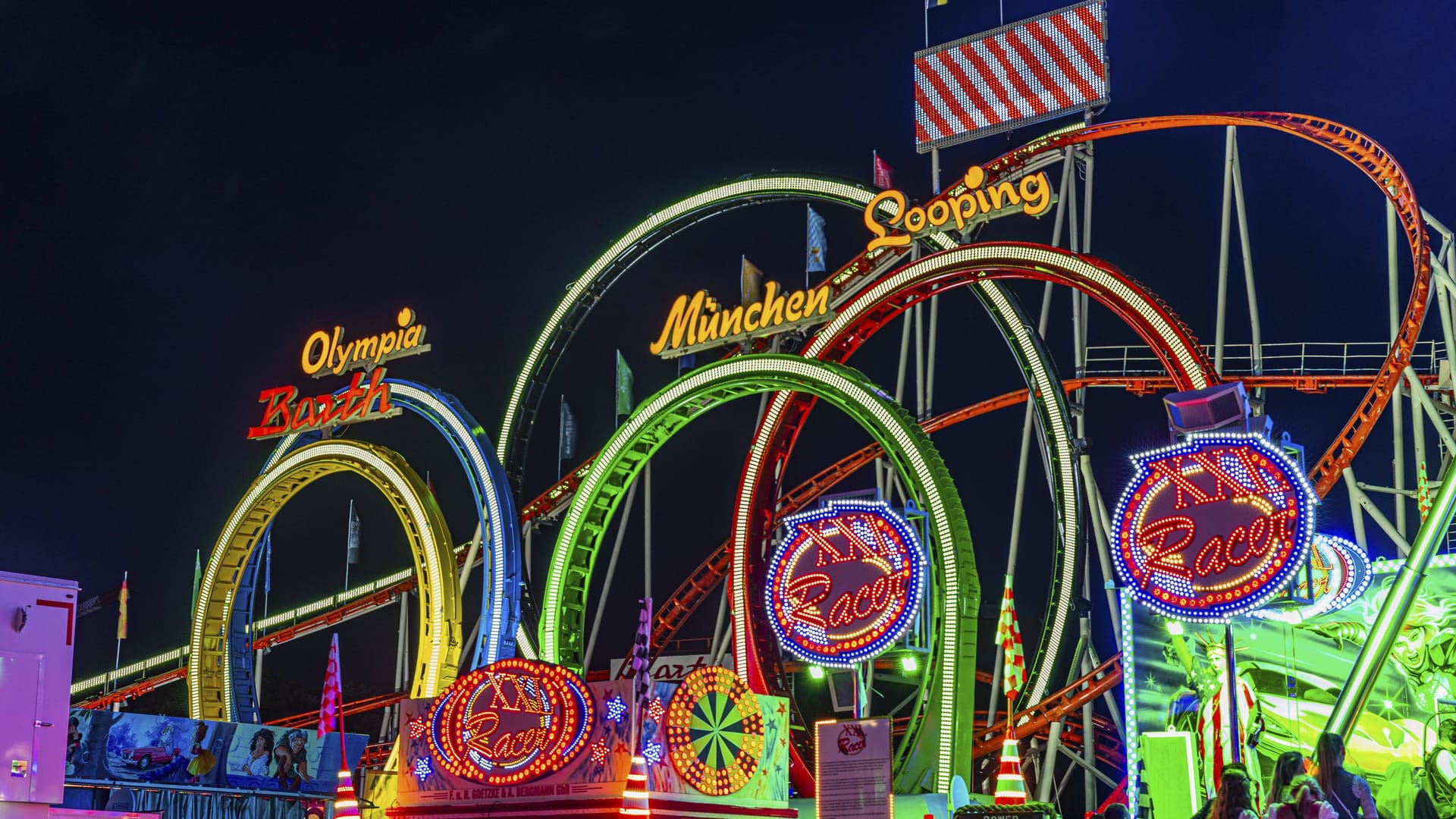 Die Achterbahn Olympia-Fünfer-Looping: So sieht es aus, wenn das Fahrgeschäft Oktoberfestwiese voll beleuchtet ist.