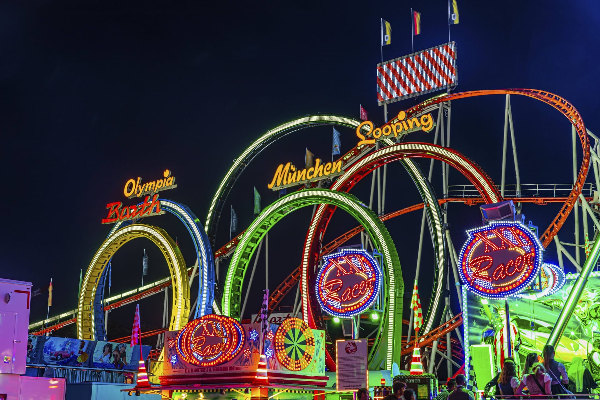 Die Achterbahn Olympia-Fünfer-Looping: So sieht es aus, wenn das Fahrgeschäft Oktoberfestwiese voll beleuchtet ist.