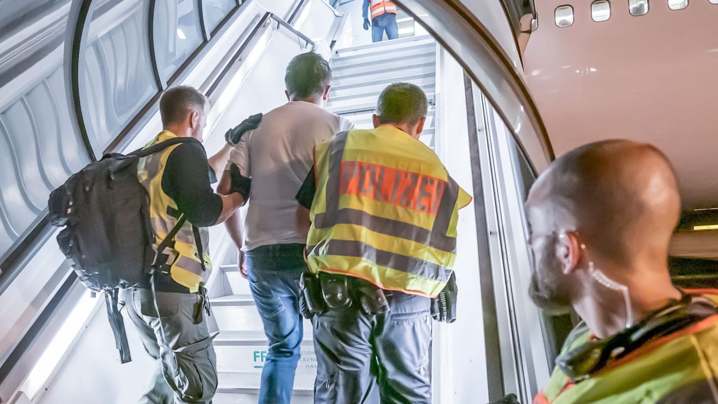 Polizeibeamte begleiten einen Afghanen auf dem Flughafen Leipzig-Halle in ein Charterflugzeug. (Archivbild)