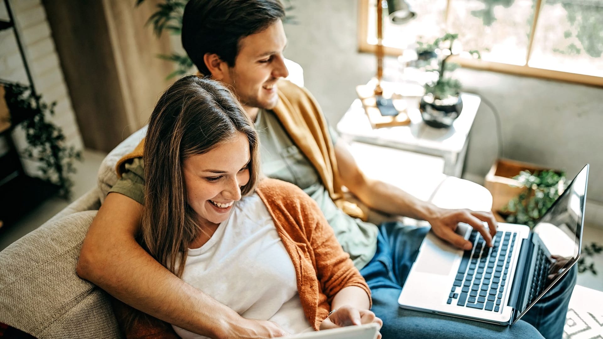 Paar sitzt bequem auf dem Sofa am Laptop