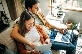 Paar sitzt bequem auf dem Sofa am Laptop