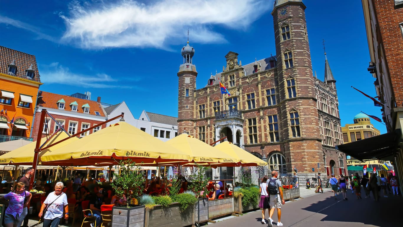 Venlo, Netherlands - July 9. 2022: Beautiful dutch square, exterior cafes and restaurants, medieval old town hall, blue summer sky