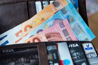 Banknoten und Bankkarten liegen in einer Geldbörse