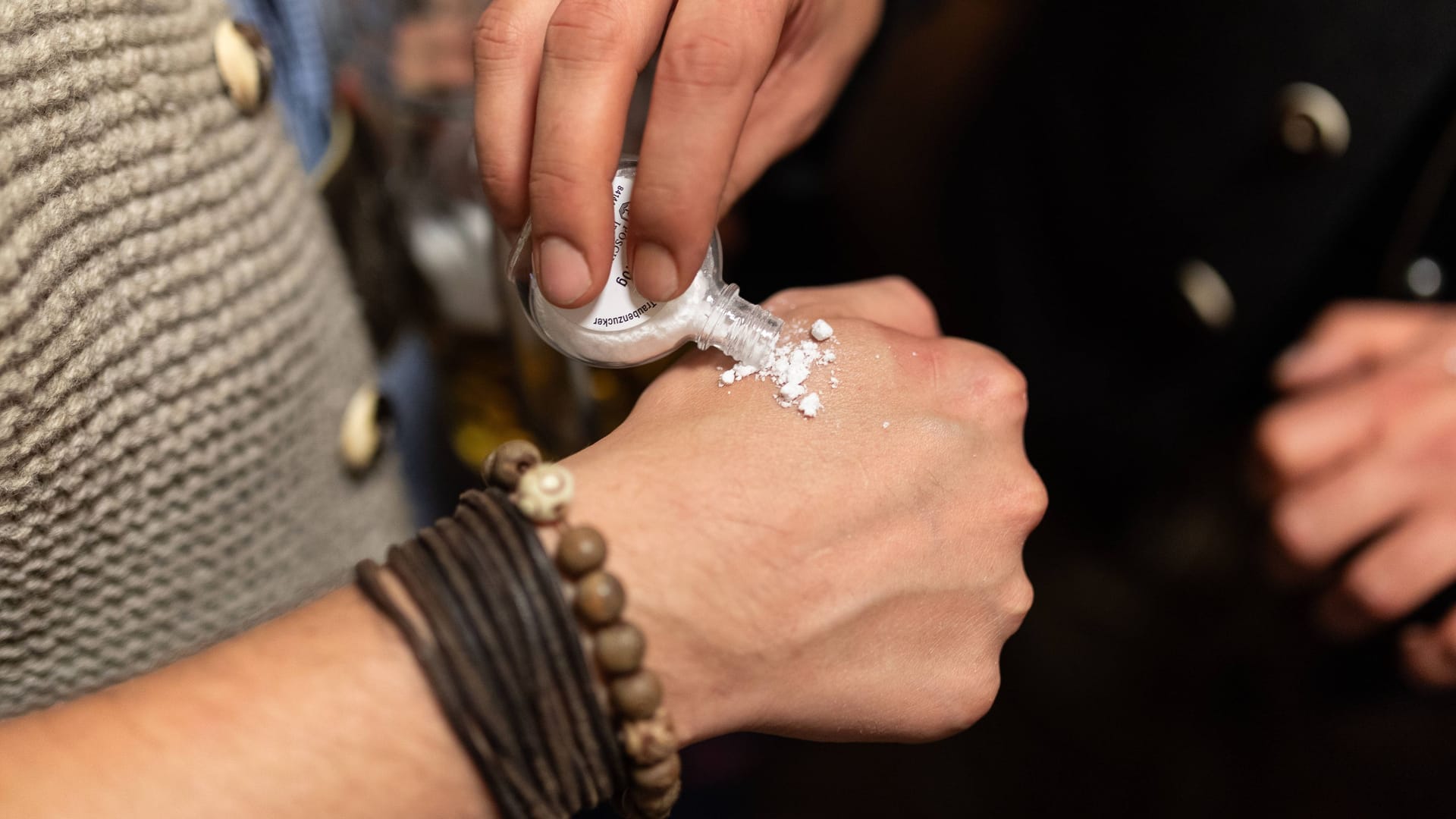 Ein Mann gibt einem anderen Mann etwas weißes Pulver auf seine Hand (Symbolbild): Eine Szene, die man auf dem Oktoberfest häufiger sieht.