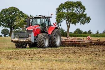 Ein Traktor fährt über ein abgeerntetes Feld auf einem landwirtschaftlichen Betrieb (Symboldbild).