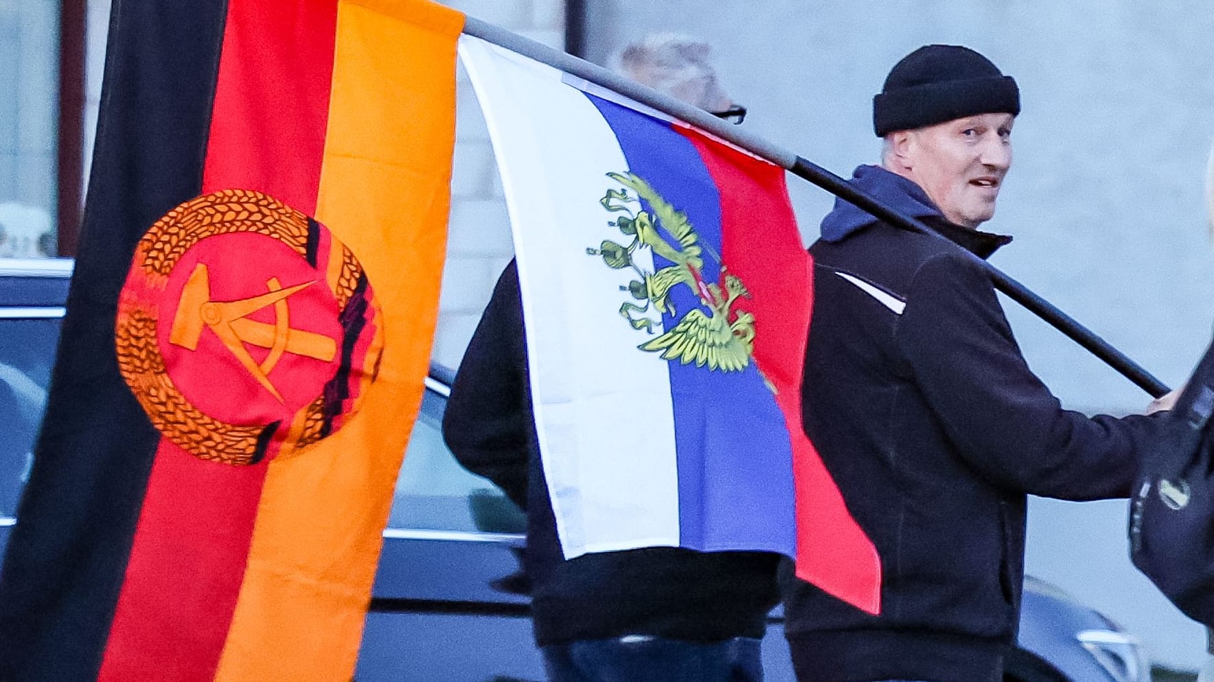 Ein Teilnehmer einer AfD-Demonstration mit Flaggen der DDR und Russland (Archivbild).