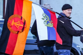 Ein Teilnehmer einer AfD-Demonstration mit Flaggen der DDR und Russland (Archivbild).