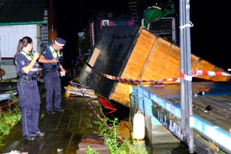 Polizisten vor der weggewehten Holzhütte: Die selbstgebaute Hütte hielt dem Unwetter nicht Stand.