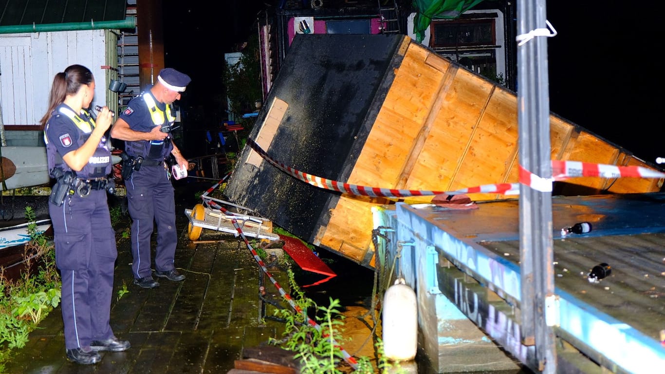 Polizisten vor der weggewehten Holzhütte: Die selbstgebaute Hütte hielt dem Unwetter nicht Stand.