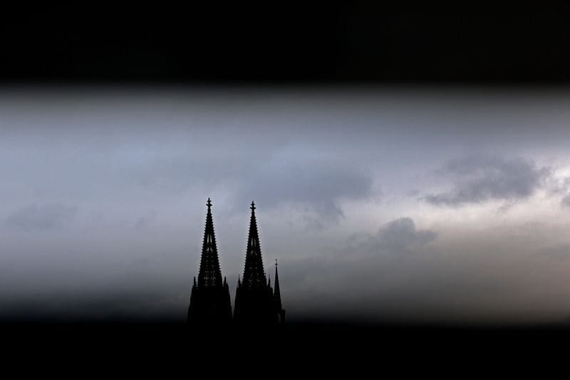 Durch ein Geländer sind die Spitzen des Domes zu sehen (Symbolbild): Im Klageverfahren gegen das Erzbistum Köln gibt es am Dienstag noch keine Entscheidung.