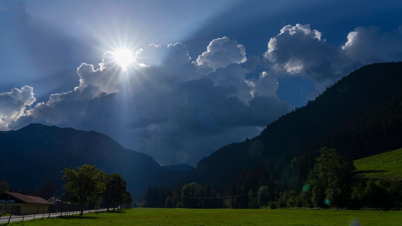 Bad Hindelang im Oberallgäu: Die Sonne sendet ihre letzten Strahlen aus, bevor sie von einer Gewitterwolke verschluckt wird.