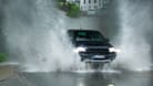 Ein Auto fährt durch Wassermassen (Symbolbild): In Österreich wird mit einem Jahrhunderthochwasser gerechnet.