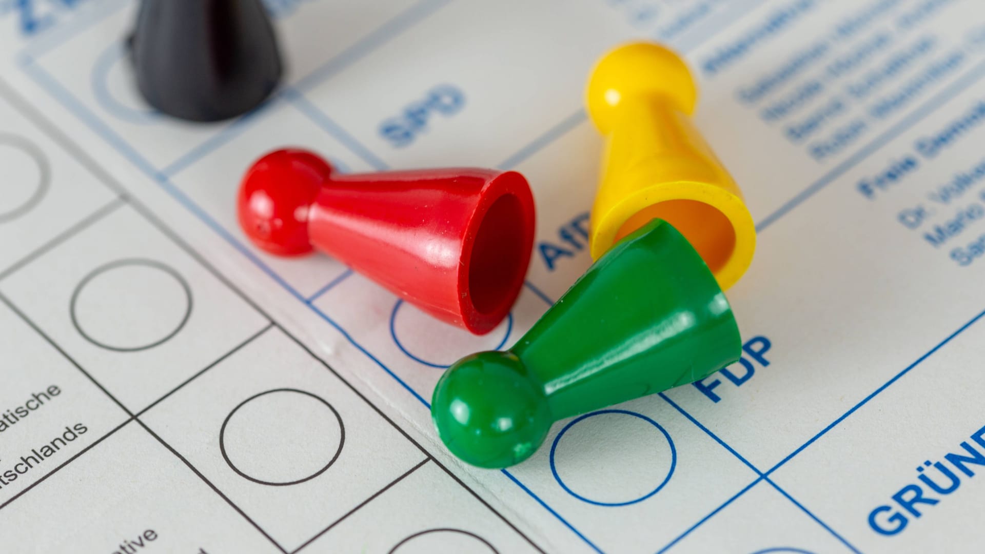Rote, grüne und gelbe Figuren liegen auf einem Wahlzettel (Symbolbild): Die Ampel will in Wandsbek regieren – die CDU in Schwarz schaut zu. Rote, grüne und gelbe Figuren liegen auf einem Wahlzettel (Symbolbild): Die Ampel will in Wandsbek regieren – die CDU in Schwarz schaut zu.