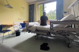 Mann sitzt auf seinem Bett im Krankenhaus(Symbolbild): Viele Patienten fürchten sich vor einer stationären Behandlung.