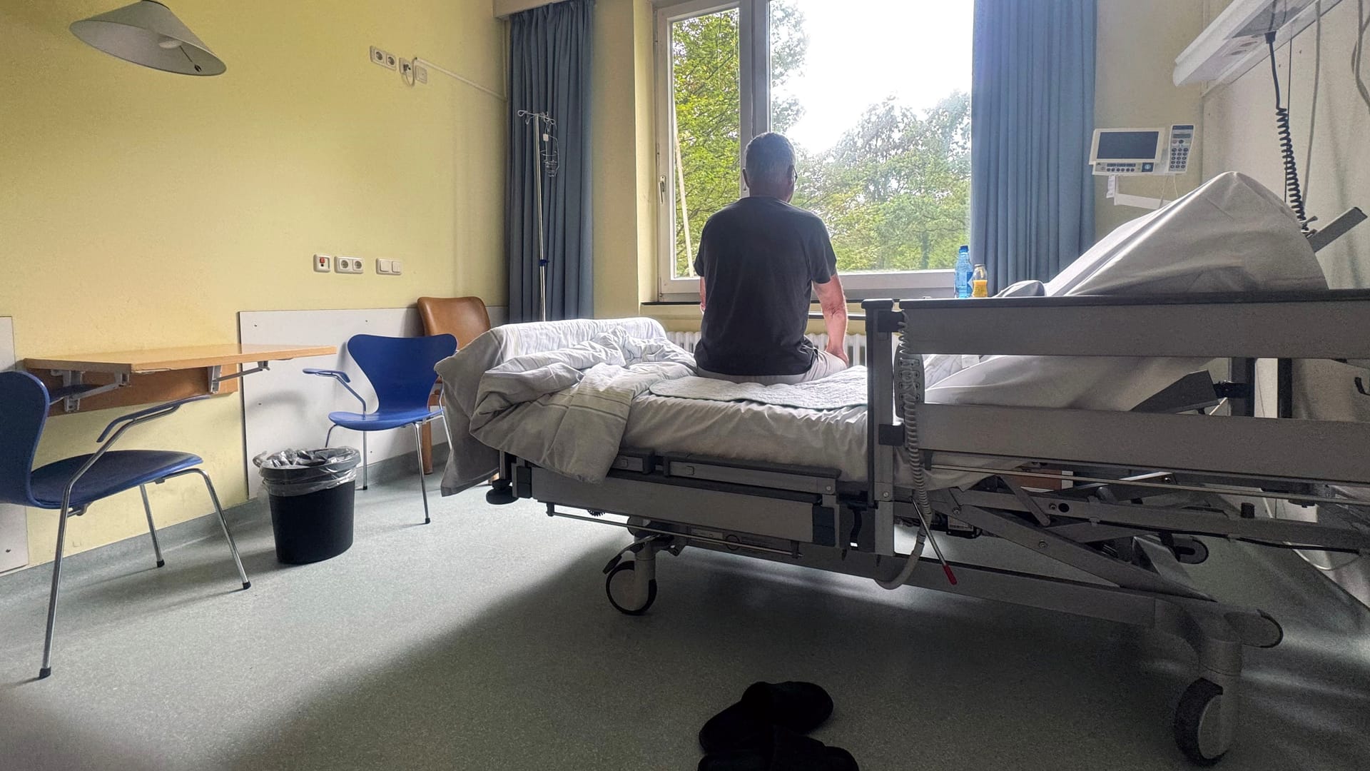 Mann sitzt auf seinem Bett im Krankenhaus(Symbolbild): Viele Patienten fürchten sich vor einer stationären Behandlung.