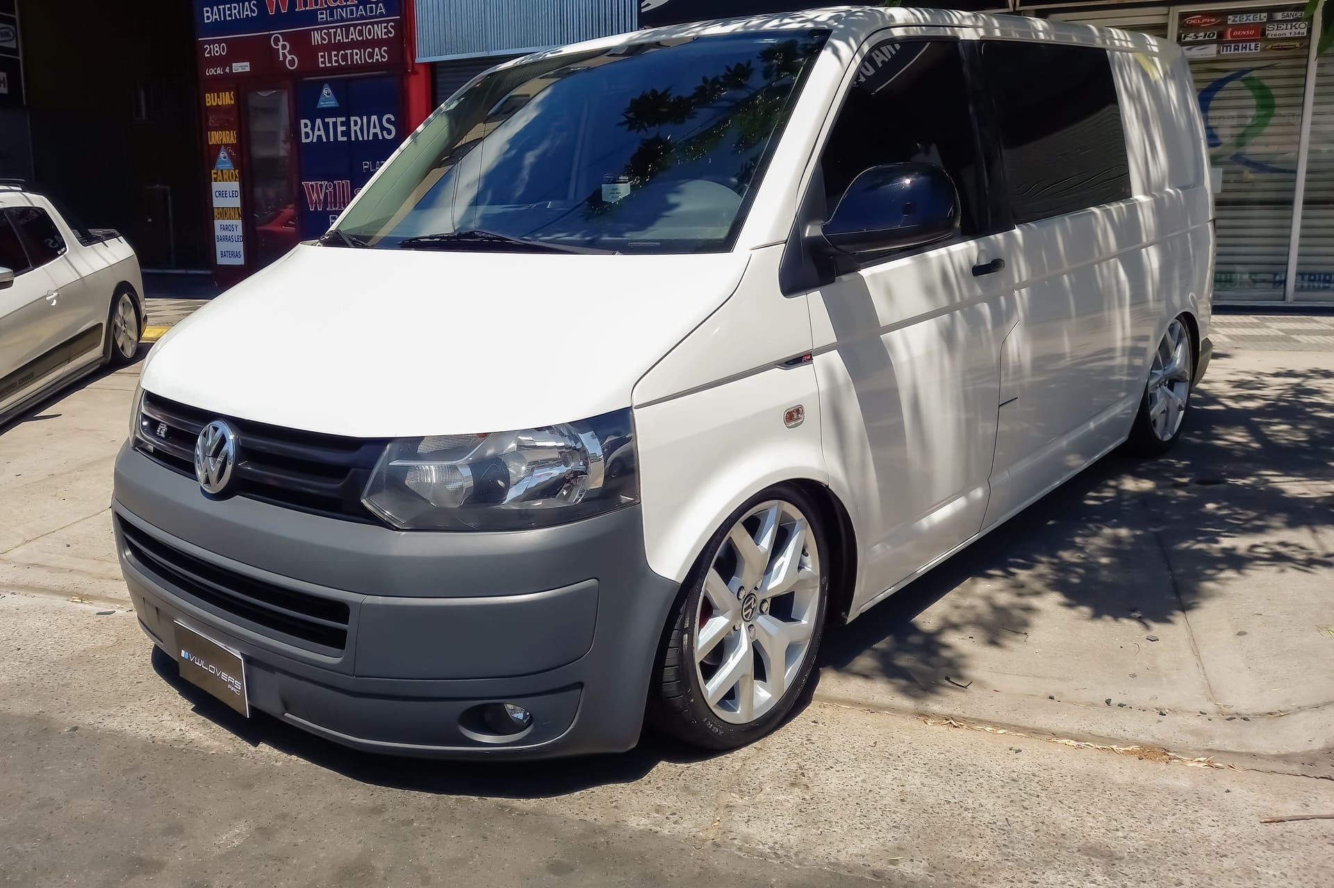 white Volkswagen Caravelle T5 Transporter van on the sidewalk Expo Warnes 2022 classic car show.