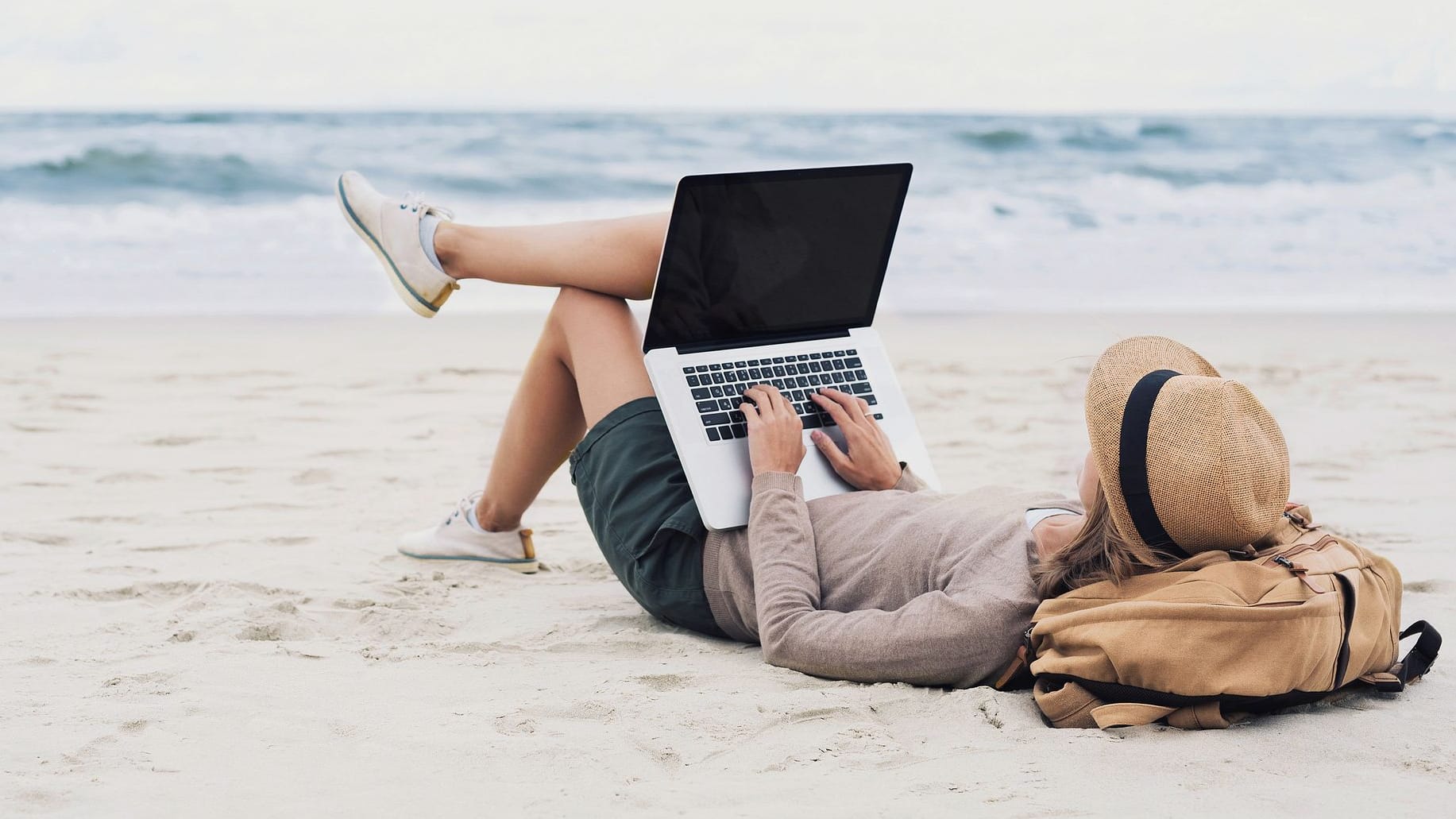 Mit dem Laptop am Strand liegen und arbeiten