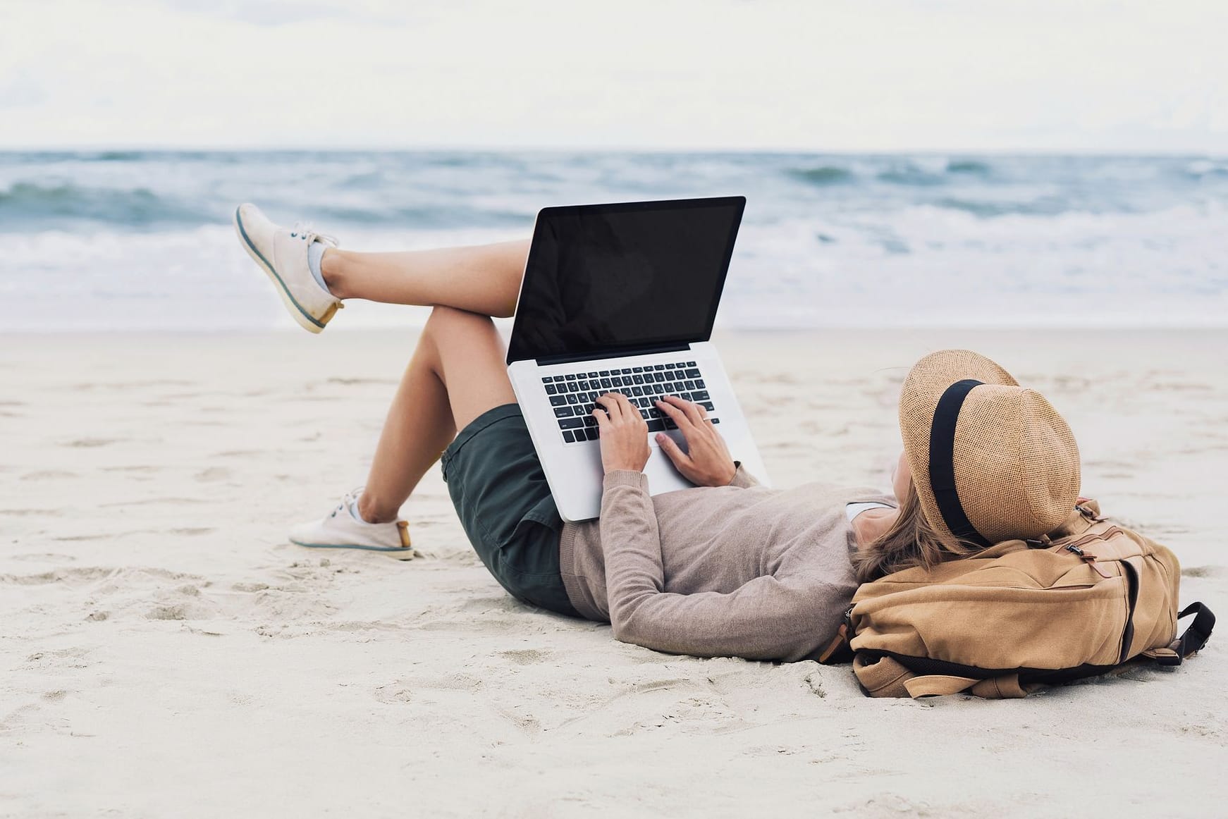 Mit dem Laptop am Strand liegen und arbeiten