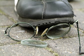 Eine Person tritt auf eine am Boden liegende Brille (Symbolbild): Ein Anhänger des 1. FC Köln wurde nach einem Pokalspiel des Frauenteams gewaltsam attackiert.