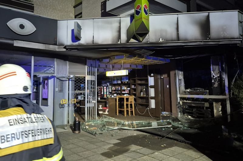 Köln: Ein Feuerwehrmann blickt auf die zerstörte Fassade der Ladenzeile mit Wohnhaus.