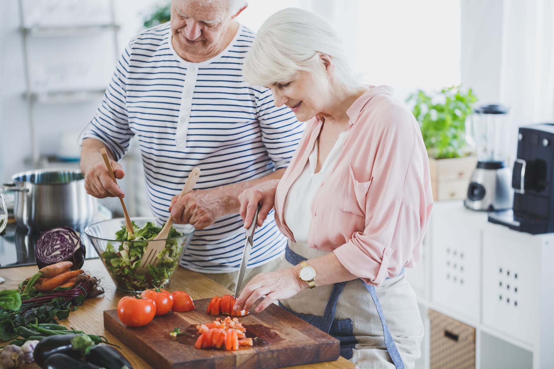 Ein Paar höheren Alters bereitet gemeinsam einen Salat zu