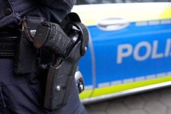 Ein Polizist steht vor einem Einsatzfahrzeug der Polizei.