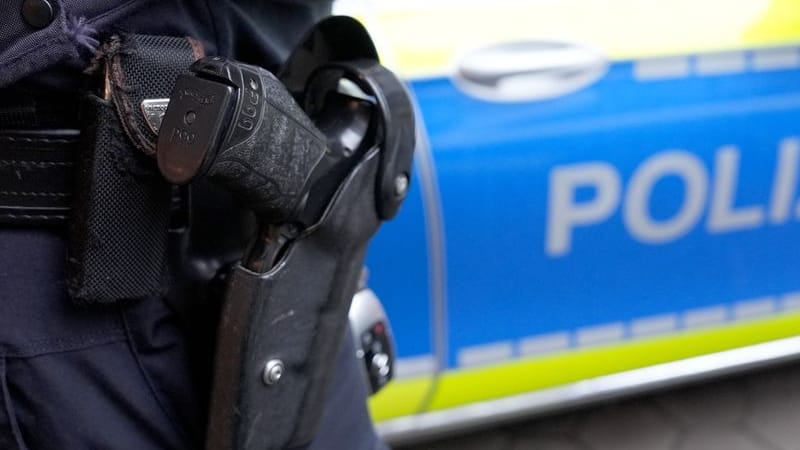 Ein Polizist steht vor einem Einsatzfahrzeug der Polizei.