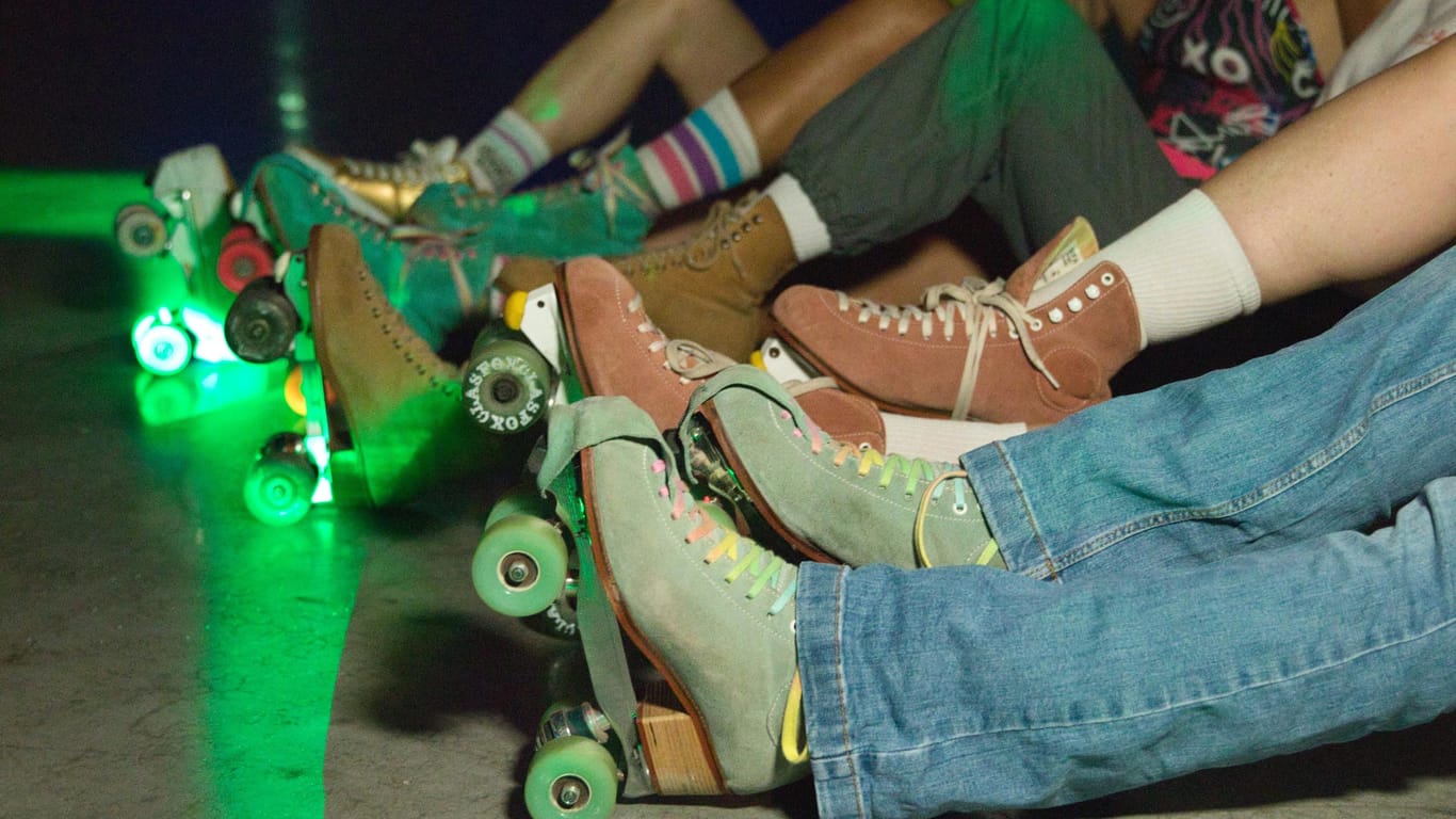 Rollschuhfahrer sitzen auf dem Boden (Symbolbild): Abends verwandelt sich die Halle in eine Roller-Disco mit Musik und Lichtershow.