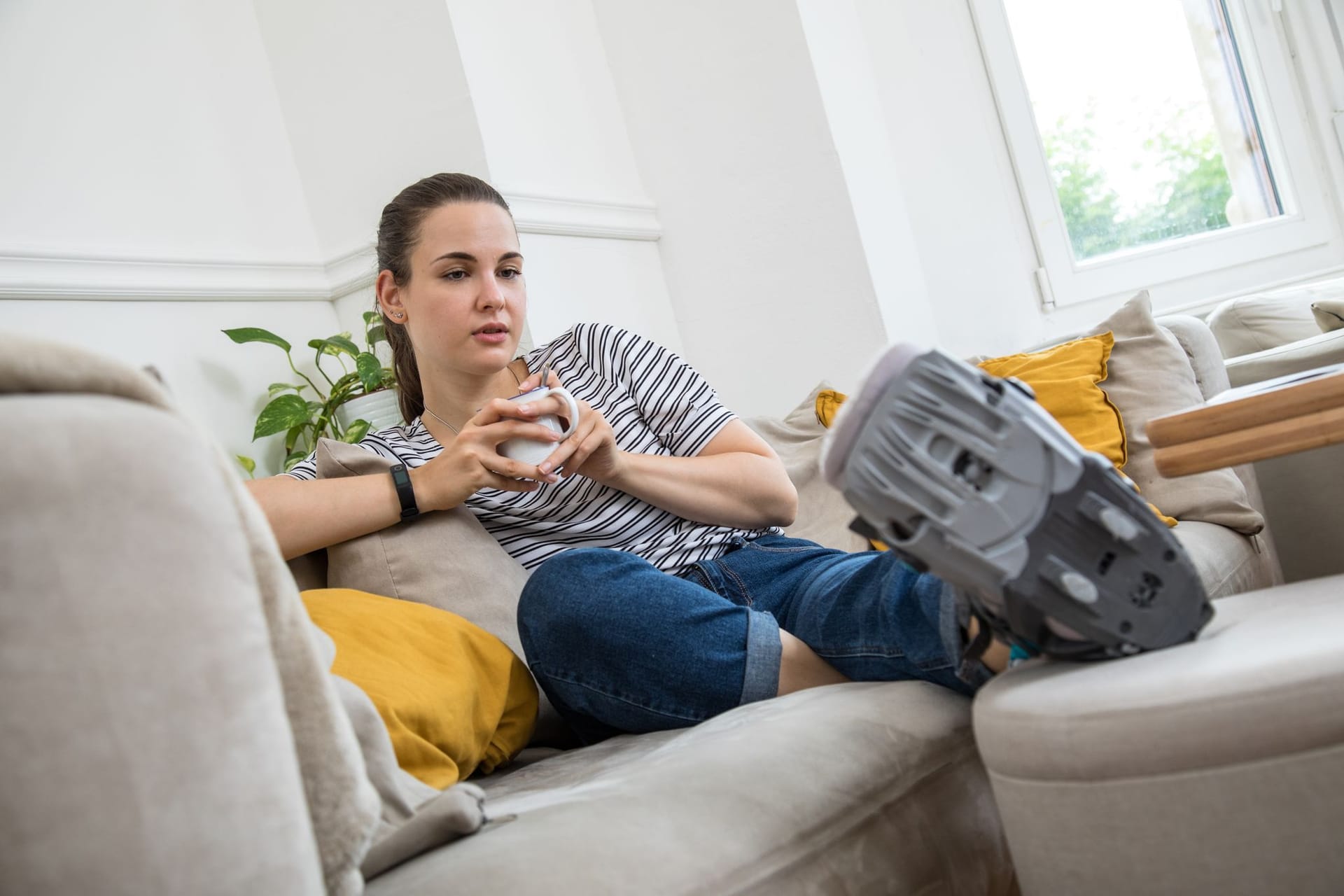 Eine Frau liegt mit einer Orthese auf dem Sofa