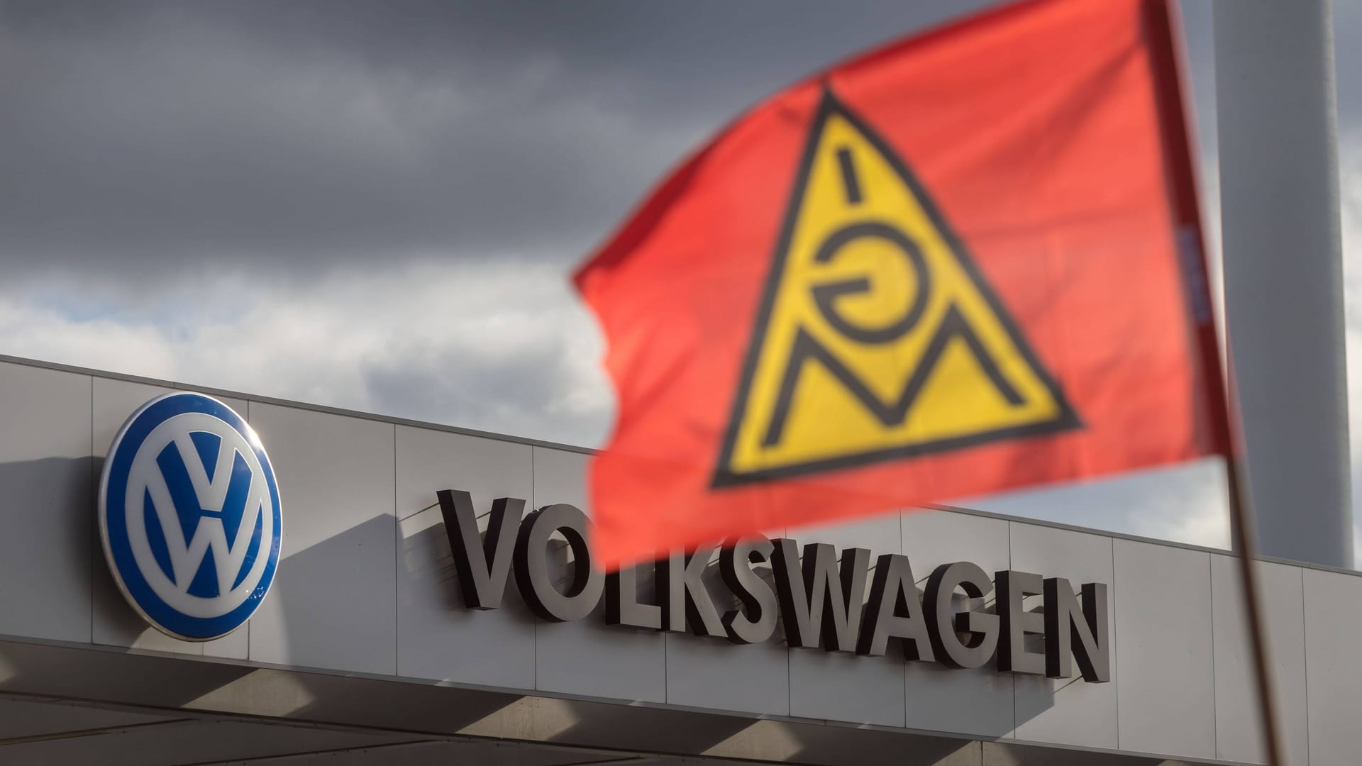 Eine Fahne von IG Metall weht vor einem Werktor vom Volkswagen: Die Gewerkschaft schließt Warnstreiks nicht aus.