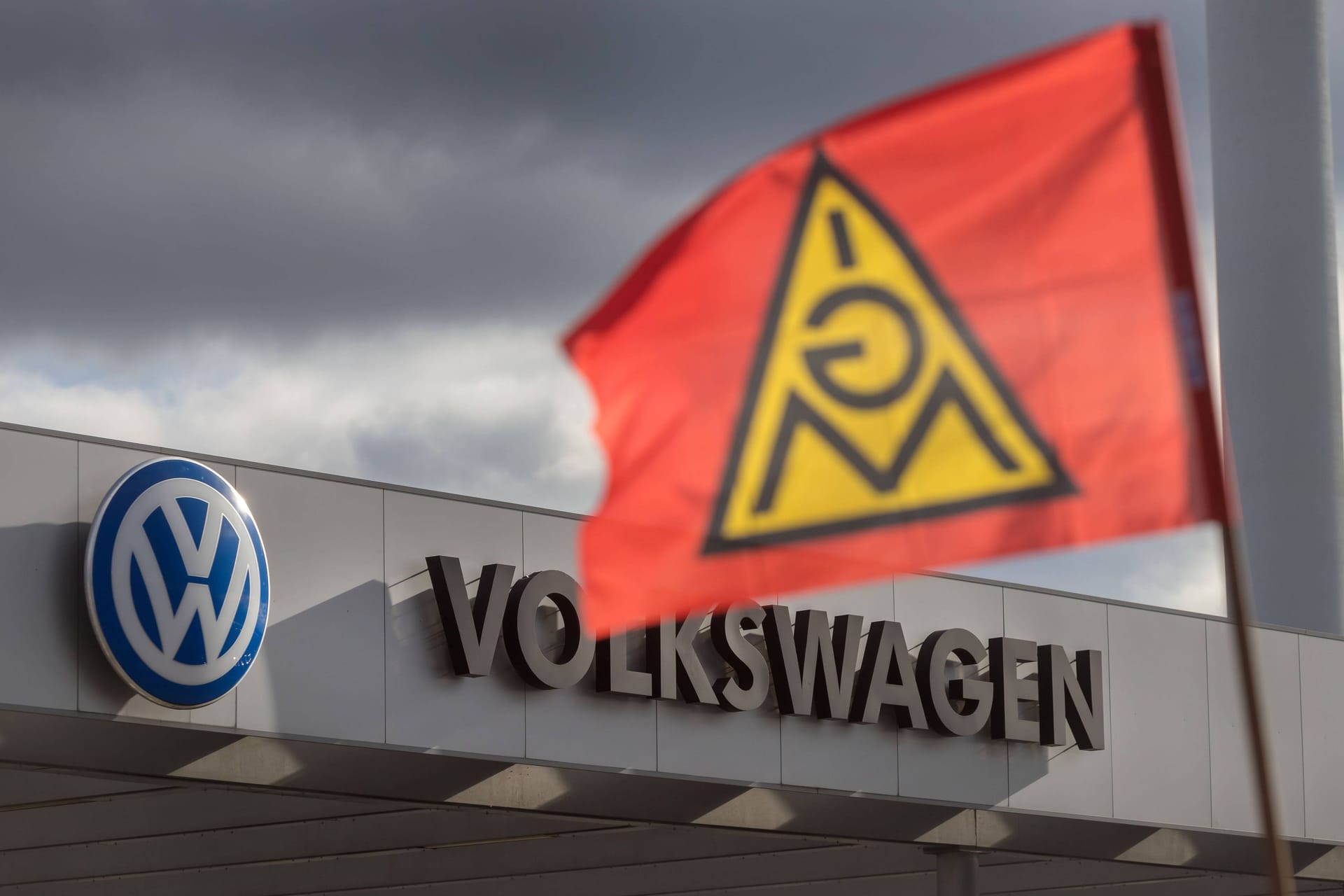 Eine Fahne von IG Metall weht vor einem Werktor vom Volkswagen: Die Gewerkschaft schließt Warnstreiks nicht aus.