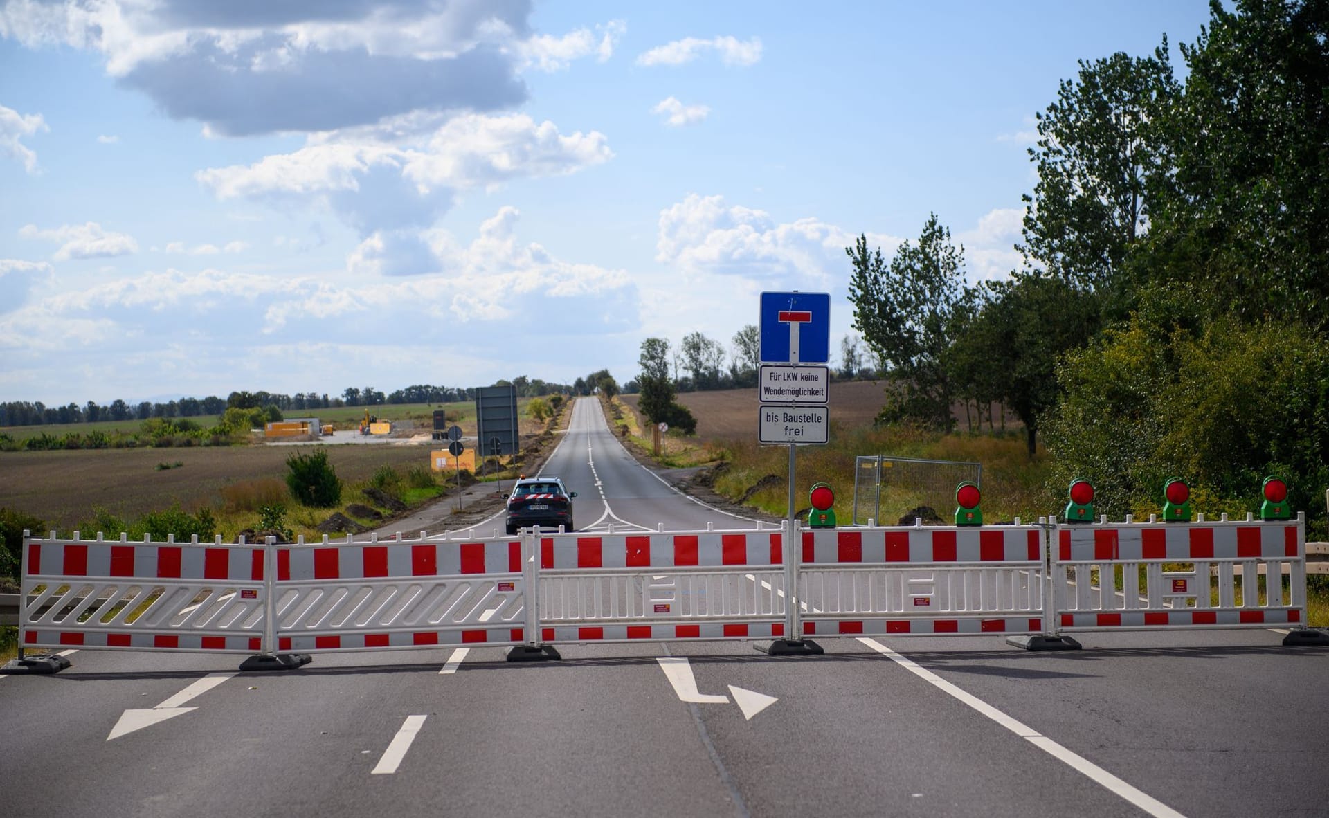 Magdeburg: Ein Baustellenfahrzeug fährt über eine gesperrte Straße zu einer Zufahrt zum Baugelände der Intel-Chipfabrik auf dem "Eulenberg".