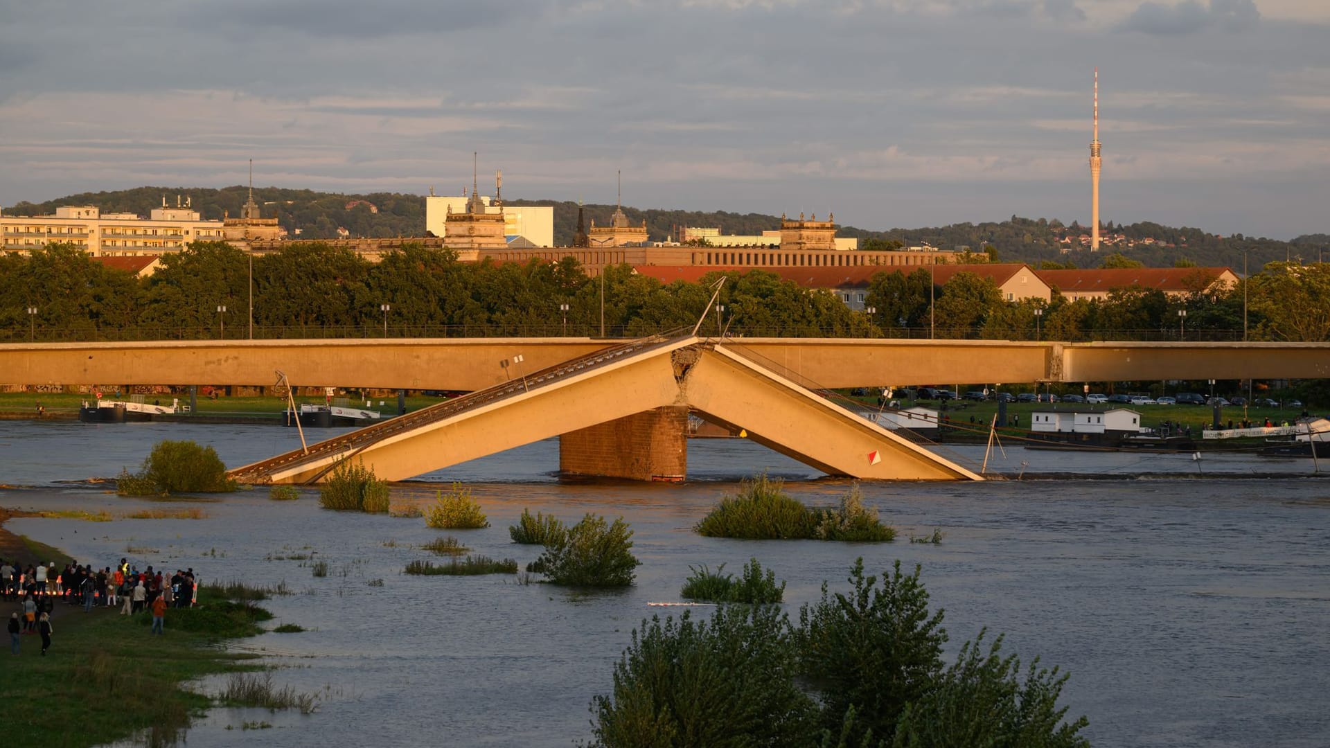 14.09.2024, Sachsen, Dresden: Wasser der Elbe läuft am Abend über Brückenteile der eingestürzten Carolabrücke. Die Abriss- und Räumungsarbeiten an der zum Teil eingestürzten Dresdner Carolabrücke sollen auf der Neustädter Seite bis zum Abend abgeschlossen sein.