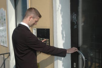 Ein Mann in Anzug klingelt an einer Haustür (Symbolfoto): Tesla-Mitarbeiter haben Hausbesuche von Chefs erhalten.