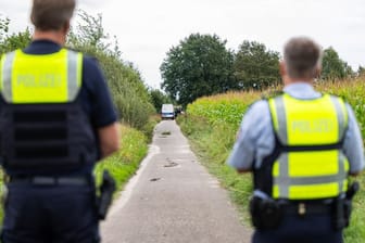 Polizeibeamte stehen am Rande eines Maisfeldes bei Gronau, wo zwei männliche Leichen gefunden wurden.