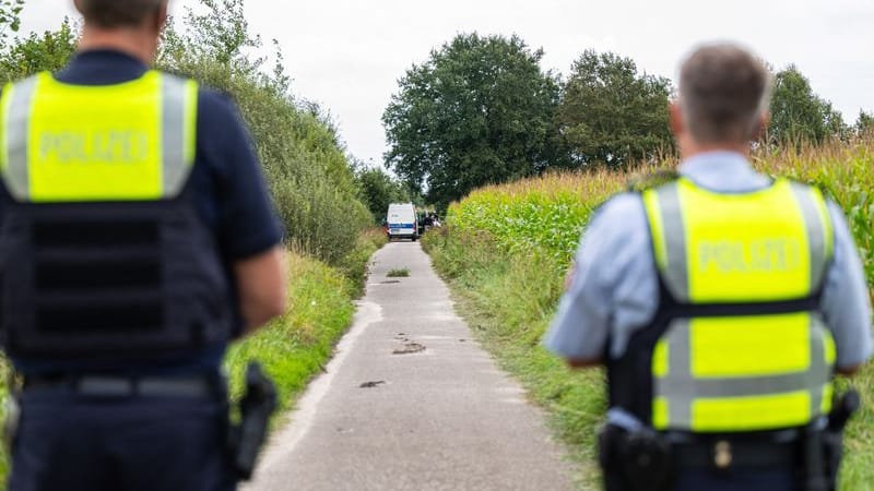 Polizeibeamte stehen am Rande eines Maisfeldes bei Gronau, wo zwei männliche Leichen gefunden wurden.