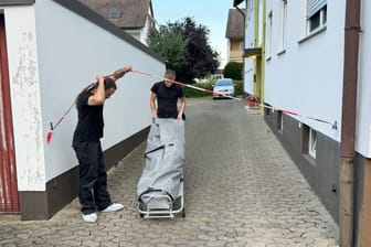 Mitarbeiter eines Bestattungsunternehmens bringen die Leiche der Frau aus ihrer Wohnung.