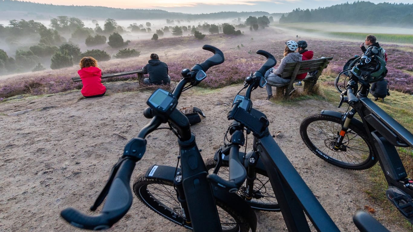 Teilnehmer einer E-Bike-Safari genießen den Sonnenaufgang in der Lüneburger Heide. Die Region ist sehr gefragt bei Touristen – auch 2024 ist das so.