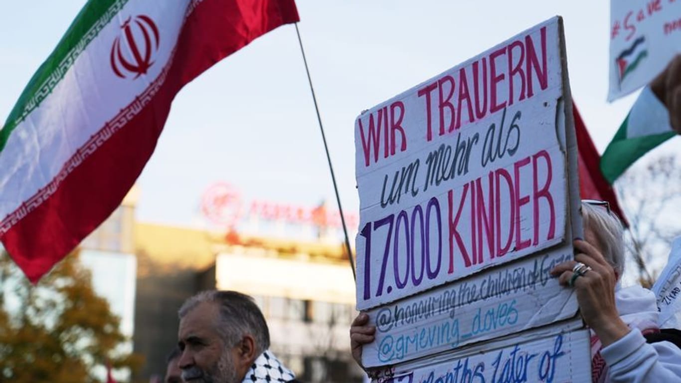 Teilnehmer einer Pro-Palästina Demonstration halten Plakate und iranische Flaggen hoch: Am Wittenbergplatz demonstrieren mehr als 300 Menschen für Solidarität mit Palästina.