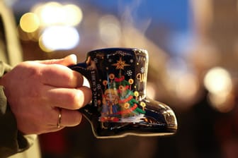 Jemand hält einen Becher Glühwein in der Hand (Symbolbild): Das Findorffer Winterdorf öffnet früher als die traditionellen Bremer Weihnachtsmärkte.