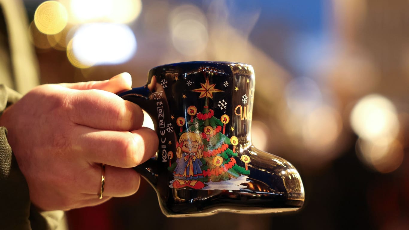 Jemand hält einen Becher Glühwein in der Hand (Symbolbild): Das Findorffer Winterdorf öffnet früher als die traditionellen Bremer Weihnachtsmärkte.