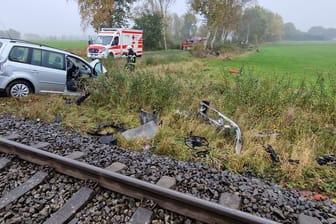 Die von der Freiwillige Feuerwehr Gemeinde Schiffdorf zur Verfügung gestellte Aufnahme zeigt Trümmerteile eines Zugs und Autos neben einer Bahnstrecke während Feuerwehr und Rettungsdienst im Einsatz sind. Für 52 Reisegäste in einem Zug Richtung Bremerhaven endete die Fahrt wegen eines Zusammenstoßes der Bahn mit einem Auto im Landkreis Cuxhaven.