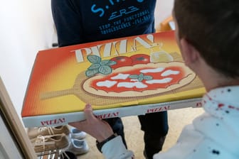 Ein Lieferant bringt einem Kunden eine Pizza nach Hause (Symbolbild): Die Kriminalpolizei ermittelt wegen versuchter räuberischer Erpressung.